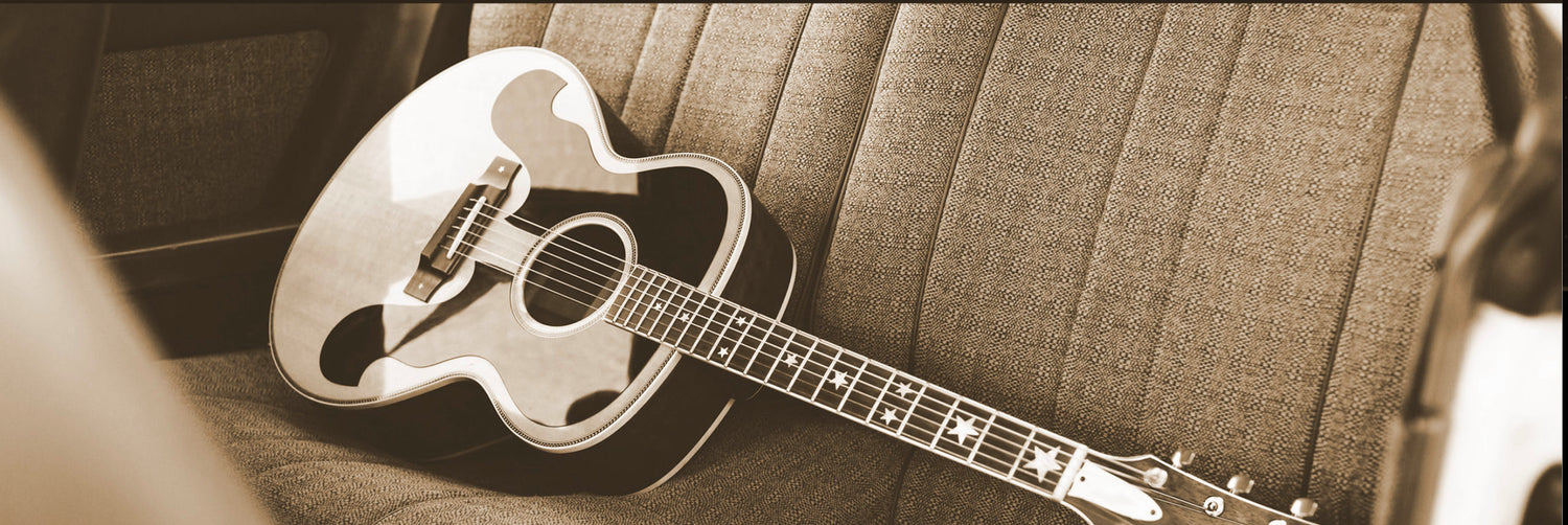 retro photograph of an acoustic guitar on the backseat of a car