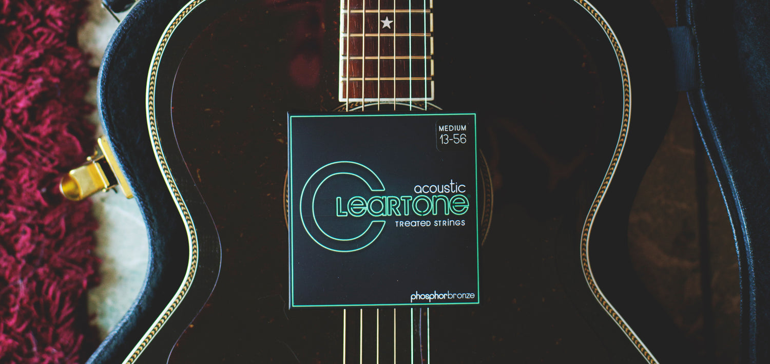 portion of an acoustic guitar with a Cleartone Strings acoustic string package on top