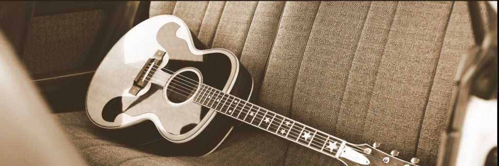 Grainy, washed-out photograph of an acoustic guitar sitting on the back seat of a car
